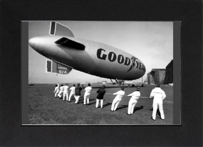 Gerahmter Druck : Die Luftschiffahrt der Goodyear Europa wird von Teams von Männern an der RAF Cardington in Position gezogen Gerahmter Druck : Die Luftschiffahrt der Goodyear Europa wird von Teams von Männern an der RAF Cardington in Position gezogen