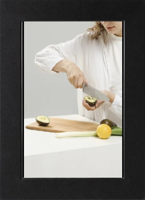 Gerahmter Druck : Eine unkenntliche Frau entfernt eine Stein aus einer Avocado mit einem Messer. Gerahmter Druck : Eine unkenntliche Frau entfernt eine Stein aus einer Avocado mit einem Messer.
