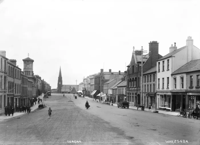 Gerahmter Druck : Lurgan - eine Straßenlandschaft mit Motorwagen, Menschen und Geschäftsfronten sowie Kirche Gerahmter Druck : Lurgan - eine Straßenlandschaft mit Motorwagen, Menschen und Geschäftsfronten sowie Kirche