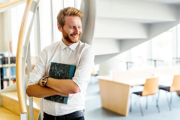 Gerahmter Druck : Hübscher intelligenter Typ liest ein Buch in einer Bibliothek. Gerahmter Druck : Hübscher intelligenter Typ liest ein Buch in einer Bibliothek.