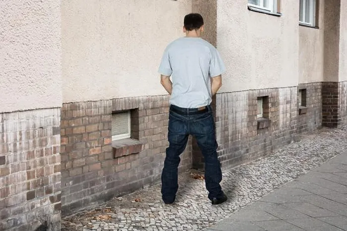 Gerahmter Druck : Ein Mann pisst an der Wand eines Gebäudes. Gerahmter Druck : Ein Mann pisst an der Wand eines Gebäudes.