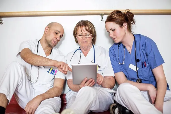 Gerahmter Druck : Ärzte verwenden digitale Tafel, während sie sich an der Wand in einem Krankenhaus lehnen. Gerahmter Druck : Ärzte verwenden digitale Tafel, während sie sich an der Wand in einem Krankenhaus lehnen.