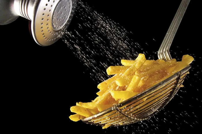 Gerahmter Druck : Chips werden mit Salz bestreut. Gerahmter Druck : Chips werden mit Salz bestreut.