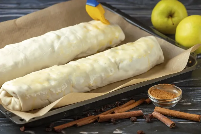 Gerahmter Druck : Zwei Apfelstrudel auf einem Backblech sind mit Butter bestrichen. Gerahmter Druck : Zwei Apfelstrudel auf einem Backblech sind mit Butter bestrichen.