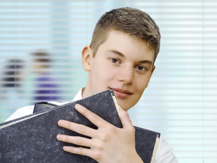 Gerahmter Druck : Praktikant oder Auszubildender hält Dateien in einem Büro. Gerahmter Druck : Praktikant oder Auszubildender hält Dateien in einem Büro.