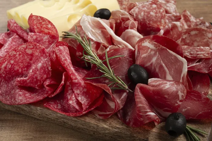 Gerahmter Druck : Frische Wurstwaren, Vorspeise, Schinken, Salami und Ham auf einem Holzbrett mit Maasdam-Käse und Oliven