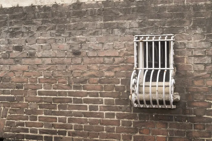 Gerahmter Druck : Gefängnisfenster in einer Ziegelmauer.