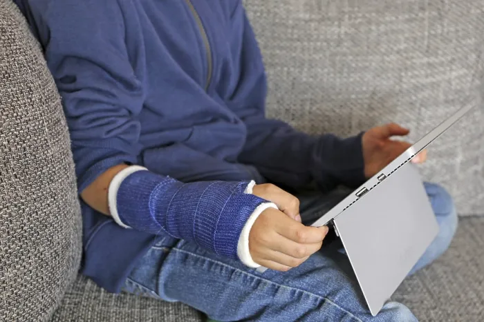 Gerahmter Druck : Junge mit Arm in Gips sitzt auf dem Sofa mit einem Tablet. Gerahmter Druck : Junge mit Arm in Gips sitzt auf dem Sofa mit einem Tablet.