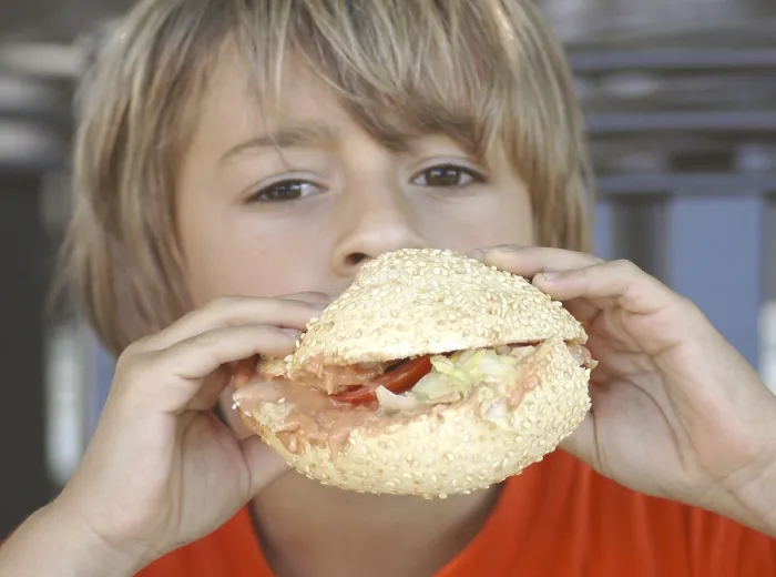 Gerahmter Druck : Junge isst Burger. Gerahmter Druck : Junge isst Burger.