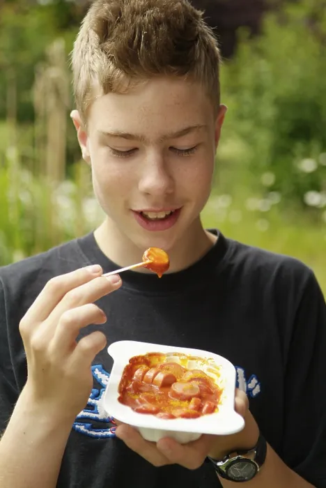 Gerahmter Druck : Junge isst Currywurst. Gerahmter Druck : Junge isst Currywurst.