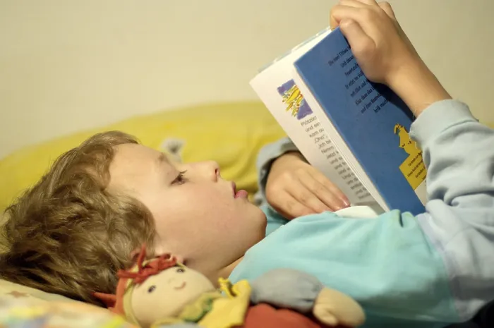 Gerahmter Druck : Junge liest im Bett.