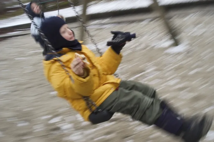 Gerahmter Druck : Ein Junge auf einer Schaukel im Winter.