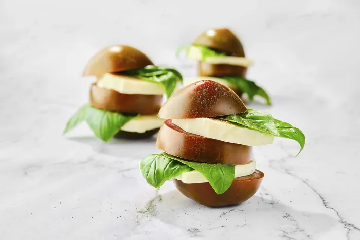 Gerahmter Druck : Brauner Schokoladen-Tomate, Mozzarella und Basilikum auf Scheiben geschnitten und auf einem Marmorhintergrund gestapelt (selektive Fokusfotografie). Gerahmter Druck : Brauner Schokoladen-Tomate, Mozzarella und Basilikum auf Scheiben geschnitten und auf einem Marmorhintergrund gestapelt (selektive Fokusfotografie).