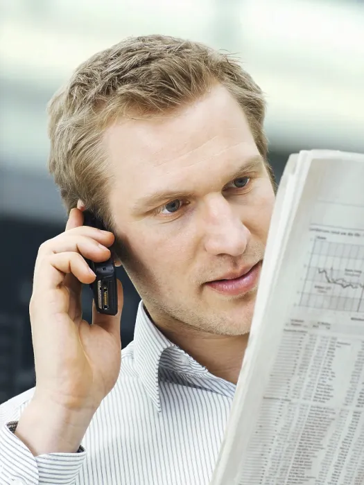 Gerahmter Druck : Unternehmer liest eine Zeitung, während er ein Mobiltelefon benutzt. Gerahmter Druck : Unternehmer liest eine Zeitung, während er ein Mobiltelefon benutzt.