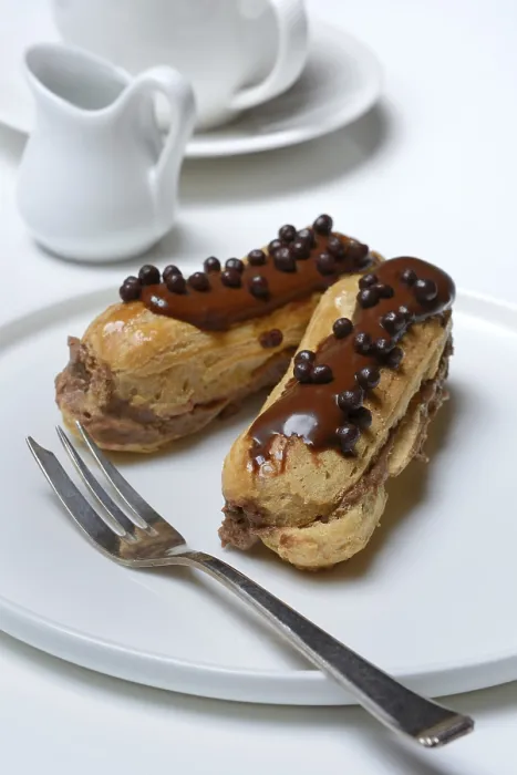 Gerahmter Druck : Zwei Schokoladen-Eclairs auf einem Teller. Gerahmter Druck : Zwei Schokoladen-Eclairs auf einem Teller.