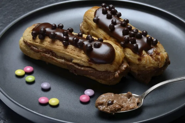 Gerahmter Druck : Zwei Schokoladen-Eclairs auf einem Teller. Gerahmter Druck : Zwei Schokoladen-Eclairs auf einem Teller.
