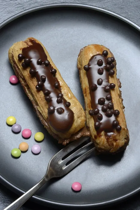 Gerahmter Druck : Zwei Schokoladen-Eclairs auf einem Teller. Gerahmter Druck : Zwei Schokoladen-Eclairs auf einem Teller.
