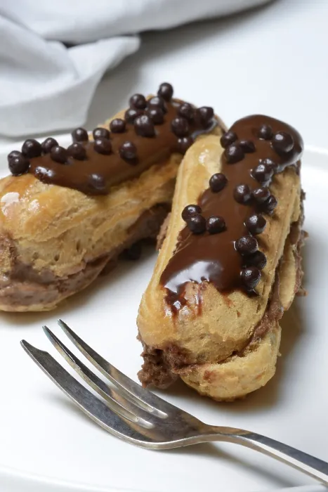 Gerahmter Druck : Zwei Schokoladen-Eclairs auf einem Teller. Gerahmter Druck : Zwei Schokoladen-Eclairs auf einem Teller.