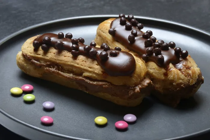 Gerahmter Druck : Zwei Schokoladen-Eclairs auf einem Teller. Gerahmter Druck : Zwei Schokoladen-Eclairs auf einem Teller.