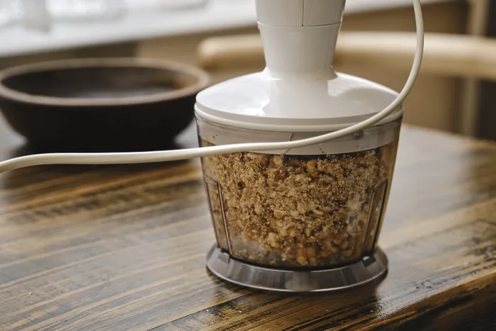 Gerahmter Druck : Walnüsse hacken in einem Foodprocessor auf einem rustikalen Holztisch. Gerahmter Druck : Walnüsse hacken in einem Foodprocessor auf einem rustikalen Holztisch.