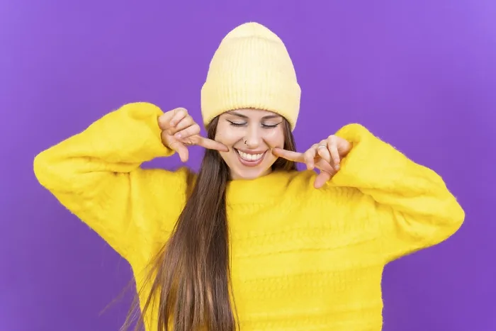 Gerahmter Druck : Enge Porträt einer jungen, fröhlichen Frau auf einem violetten Studiobackground in einem gelben Wollepulli lächelnd isoliert. Gerahmter Druck : Enge Porträt einer jungen, fröhlichen Frau auf einem violetten Studiobackground in einem gelben Wollepulli lächelnd isoliert.