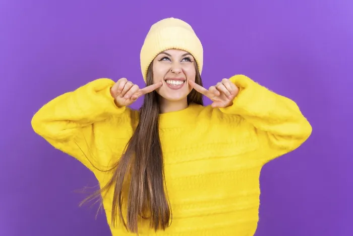 Gerahmter Druck : Nahe Portrait einer jungen, fröhlichen Frau auf einem violetten Studiohintergrund isoliert in einem gelben Wollepulli lächelnd. Gerahmter Druck : Nahe Portrait einer jungen, fröhlichen Frau auf einem violetten Studiohintergrund isoliert in einem gelben Wollepulli lächelnd.