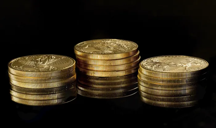 Gerahmter Druck : Enge Aufnahme eines ein-Unzen-Solidgold-Eagles-Münzstücks, das auf anderen Münzen gestapelt ist und in einer schwarzen Oberfläche widergespiegelt wird. Gerahmter Druck : Enge Aufnahme eines ein-Unzen-Solidgold-Eagles-Münzstücks, das auf anderen Münzen gestapelt ist und in einer schwarzen Oberfläche widergespiegelt wird.