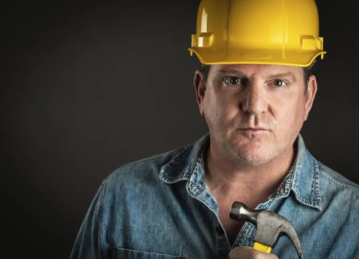 Gerahmter Druck : Erfahrener Bauunternehmer in Helm mit Hammer, unter dramatischem Licht. Gerahmter Druck : Erfahrener Bauunternehmer in Helm mit Hammer, unter dramatischem Licht.
