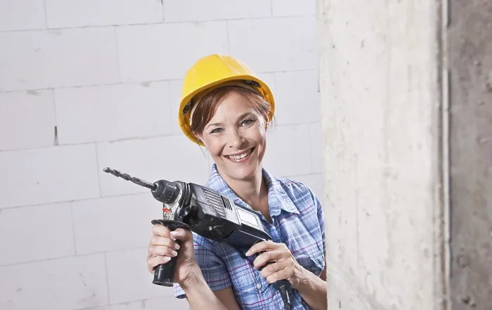 Gerahmter Druck : Handwerkerin mit Helm und Bohrmaschine.