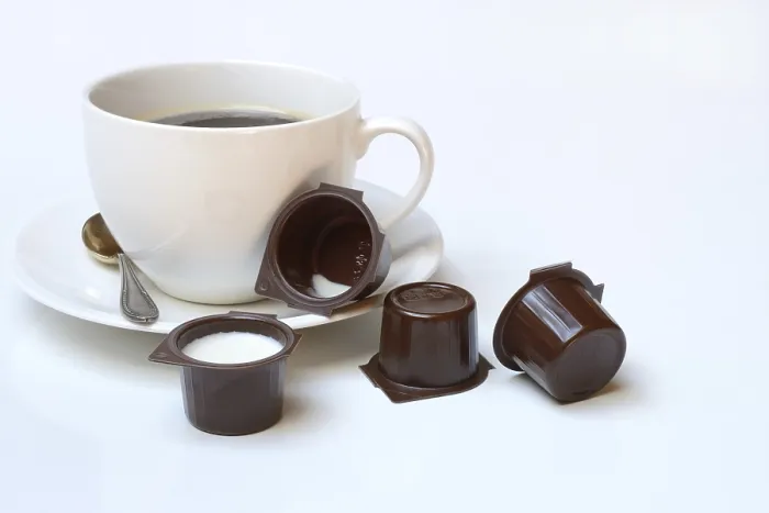 Gerahmter Druck : Kaffeebecher mit Milch in Portionspackung Gerahmter Druck : Kaffeebecher mit Milch in Portionspackung