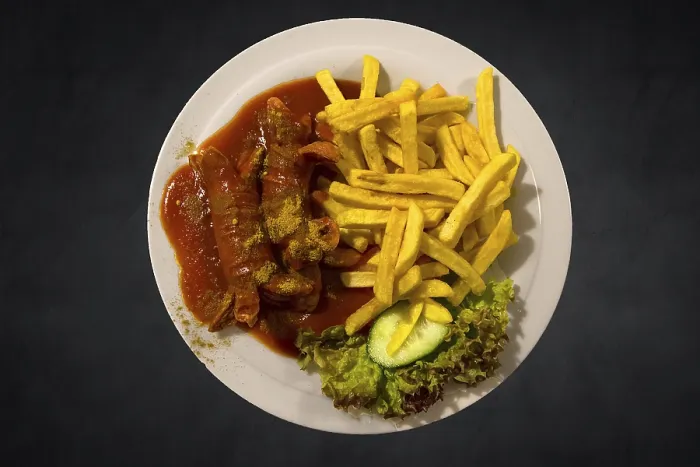 Gerahmter Druck : Currywurst mit Pomfritten auf einem dunklen Hintergrund. Gerahmter Druck : Currywurst mit Pomfritten auf einem dunklen Hintergrund.