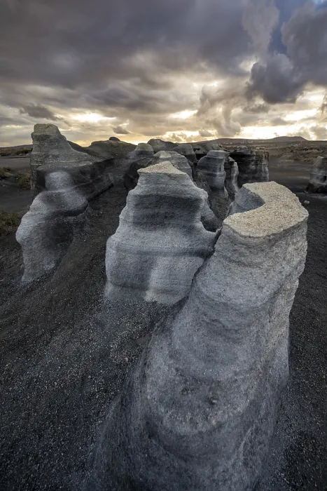 Gerahmter Druck : Erosionsschuttformationen, vulkanische Landschaft mit dramatischem wolkenverhangenen Himmel bei Sonnenuntergang. Gerahmter Druck : Erosionsschuttformationen, vulkanische Landschaft mit dramatischem wolkenverhangenen Himmel bei Sonnenuntergang.
