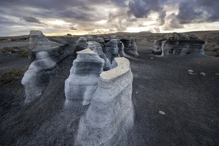 Gerahmter Druck : Erosionierte Felsformationen, vulkanisches Landschaft mit dramatischem wolkenverhangenen Himmel am Sonnenuntergang. Gerahmter Druck : Erosionierte Felsformationen, vulkanisches Landschaft mit dramatischem wolkenverhangenen Himmel am Sonnenuntergang.