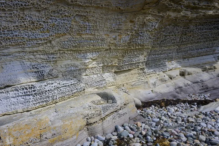 Gerahmter Druck : Erosierte Felsen mit komplexer Textur an einer Küste, die von kleinen Kieseln umgeben ist. Gerahmter Druck : Erosierte Felsen mit komplexer Textur an einer Küste, die von kleinen Kieseln umgeben ist.