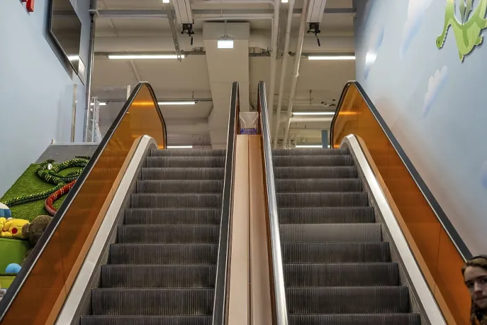 Gerahmter Druck : Oberseite einer Rolltreppe mit orangefarbenen Glasabsperrungen.
