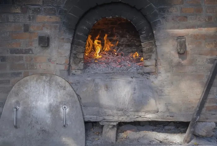 Gerahmter Druck : Das Feuer für einen traditionellen Brotbackofen anmachen. Gerahmter Druck : Das Feuer für einen traditionellen Brotbackofen anmachen.