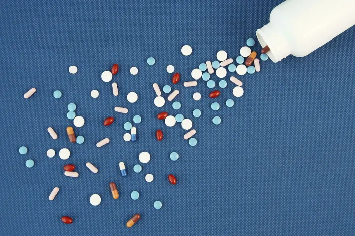 Gerahmter Druck : Gruppe verschiedener Tabletten und Kapseln, die aus einem weißen Flaschen herausfallen. Gerahmter Druck : Gruppe verschiedener Tabletten und Kapseln, die aus einem weißen Flaschen herausfallen.