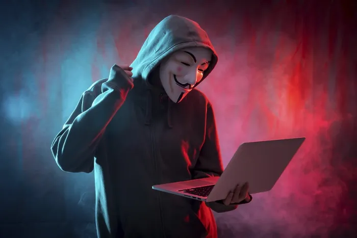 Gerahmter Druck : Ein Hacker mit einer anonymen Maske, einem Computer und ein Kampfsymbol.