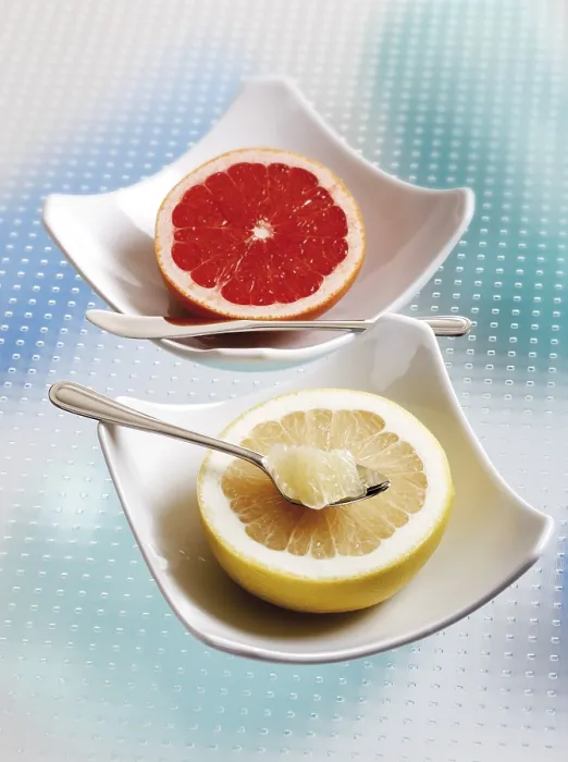 Gerahmter Druck : Die Hälfte einer Grapefruit und eine Rosenkirsche in Porzellanbechern. Gerahmter Druck : Die Hälfte einer Grapefruit und eine Rosenkirsche in Porzellanbechern.