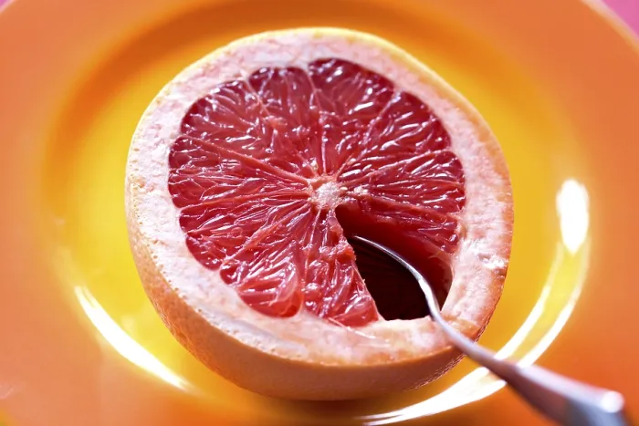 Gerahmter Druck : Gekochelte Grapefruit halbiert mit Löffel auf einem Teller. Gerahmter Druck : Gekochelte Grapefruit halbiert mit Löffel auf einem Teller.
