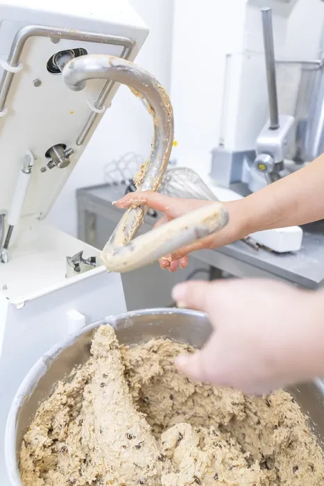 Gerahmter Druck : Eine Hand greift eine mit Teig gefüllte Mischmaschine. Gerahmter Druck : Eine Hand greift eine mit Teig gefüllte Mischmaschine.