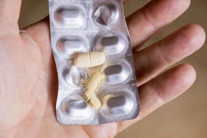 Gerahmter Druck : Händedruck, der ein Blisterpäckchen mit Tabletten hält. Gerahmter Druck : Händedruck, der ein Blisterpäckchen mit Tabletten hält.