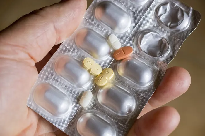Gerahmter Druck : Eine Hand hält ein Blisterpäckchen mit Tabletten. Gerahmter Druck : Eine Hand hält ein Blisterpäckchen mit Tabletten.