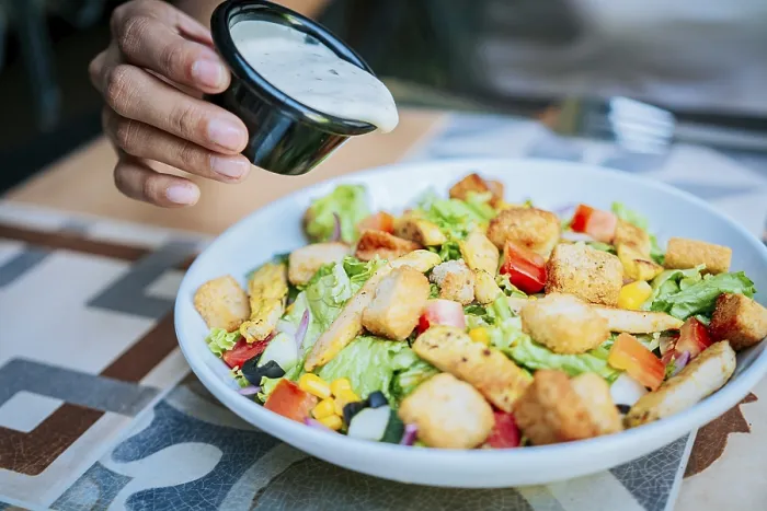 Gerahmter Druck : Die Hand gibt Dressing auf ein Caesar-Salat. Gerahmter Druck : Die Hand gibt Dressing auf ein Caesar-Salat.