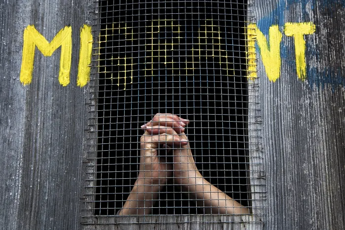Gerahmter Druck : Hände hinter Gittern, Graffito mit dem Text 'Migrant' Gerahmter Druck : Hände hinter Gittern, Graffito mit dem Text 'Migrant'