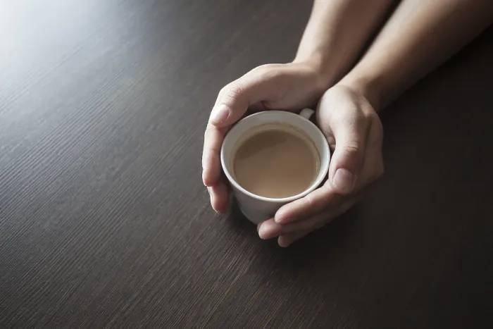 Gerahmter Druck : Hände halten einen heißen Kaffeebecher auf einem Tisch.