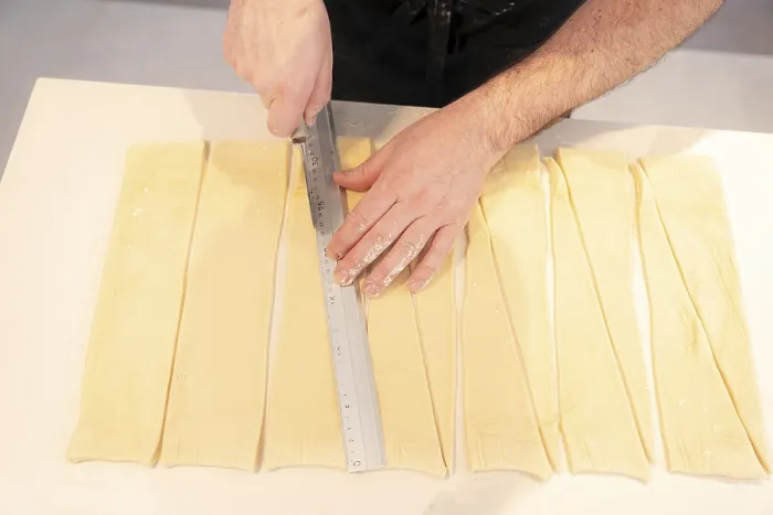 Gerahmter Druck : Ein Detail der Hände eines Mannes, der Croissants backt, beim Anbringen von dreieckigen Schnitten in die Blasenmischung. Gerahmter Druck : Ein Detail der Hände eines Mannes, der Croissants backt, beim Anbringen von dreieckigen Schnitten in die Blasenmischung.