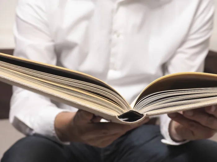 Gerahmter Druck : Ein attraktiver Mann liest ein altes Buch auf einem Sofa. Gerahmter Druck : Ein attraktiver Mann liest ein altes Buch auf einem Sofa.