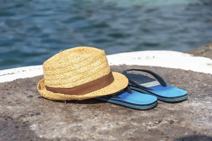 Gerahmter Druck : Hut und Flipflops neben einem Naturpool.