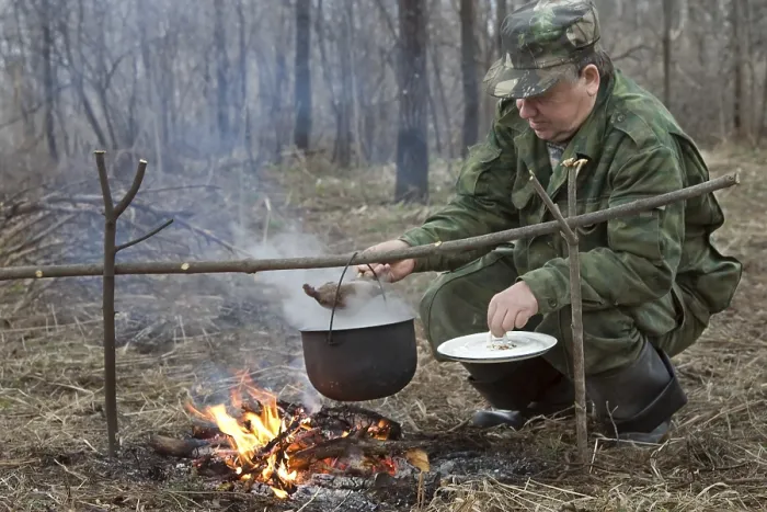 Gerahmter Druck : Der Jäger macht ein Abendessen auf einem Feuer. Gerahmter Druck : Der Jäger macht ein Abendessen auf einem Feuer.
